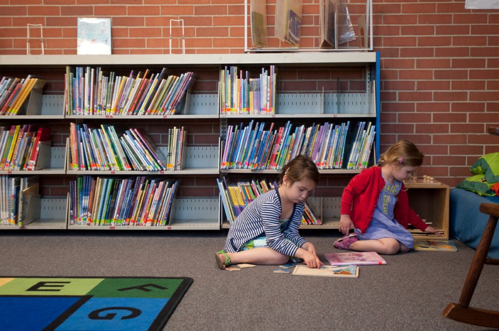 Kids reading on the floor near bookshelves